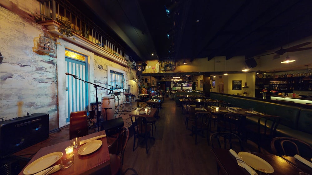 Interior view of Cafe La Trova, showcasing a vibrant and rustic atmosphere with wooden tables, chairs, and a stage setup for live music.