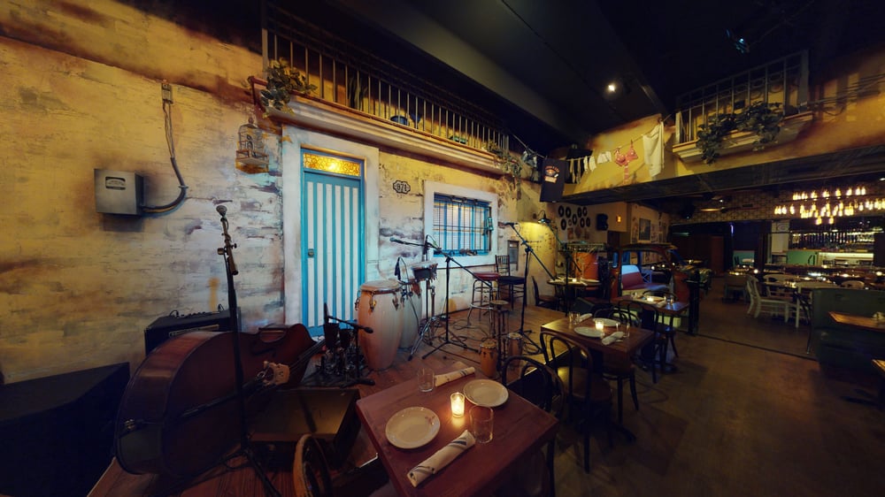 Interior of Cafe La Trova showcasing retro decor with musical instruments, tables, and lighting, creating an inviting atmosphere for dining and live music.